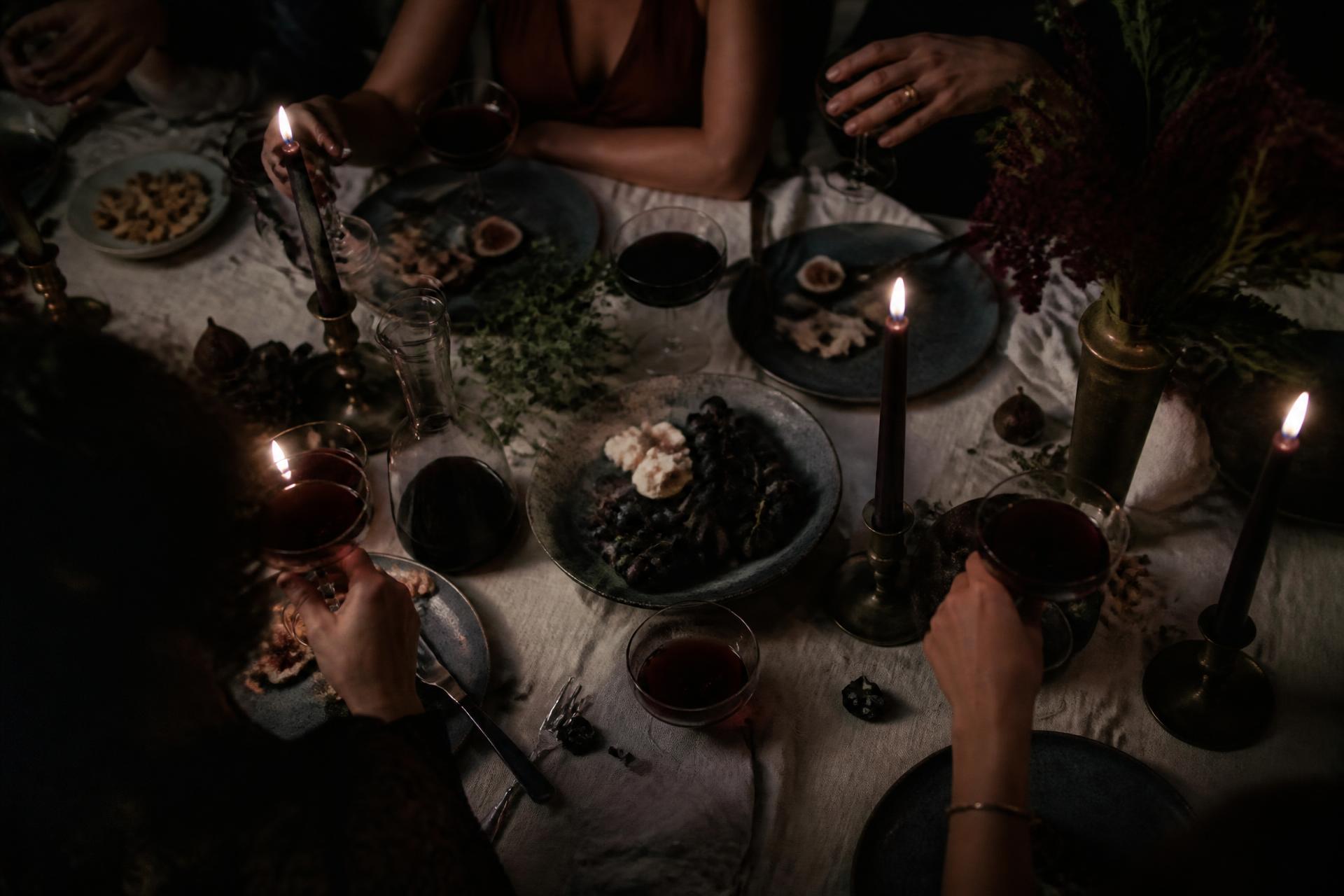 Candlelit dinner table with wine, figs and ceramics in warm low light